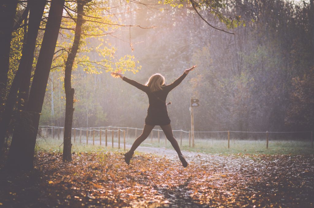 Woman jumping for joy in the woods.