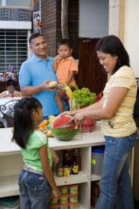 Mother slicing watermelon with father and children watching