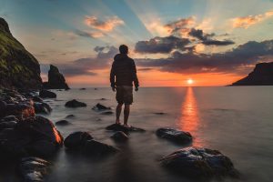 man standing facing the sunrise
