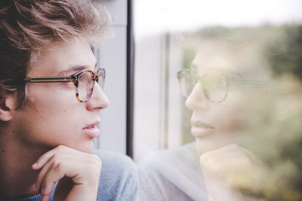 boy with glasses looking out the window