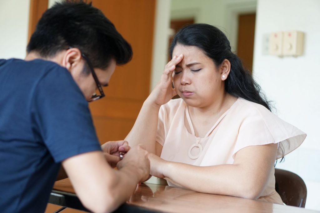 woman holding forehead in front of man
