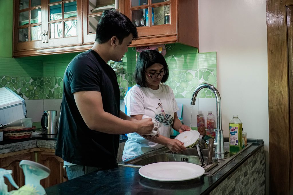 man and woman washing dishes together