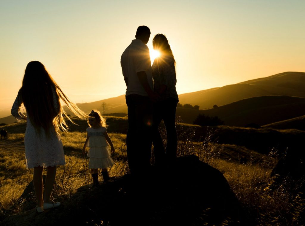 man and woman together with children on a field of grass